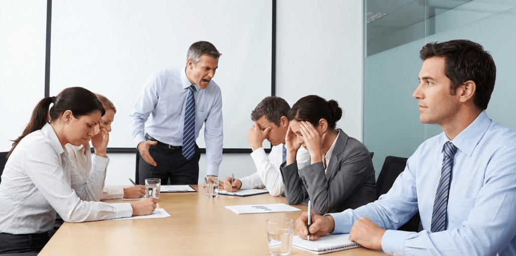 In questa prima immagine, l'ambiente di lavoro è chiaramente caotico e stressante, con colleghi che litigano e un senso di urgenza. La persona in primo piano, tuttavia, è un'oasi di calma, concentrata sul suo lavoro e protetta dalle sue cuffie e dal suo atteggiamento sereno.